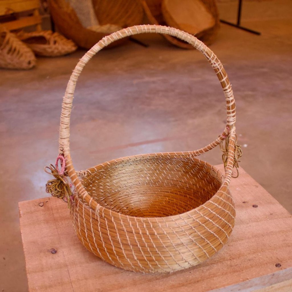 Golden grass harvester basket on picnic table. Made by artisans in Mumbuca Brazil