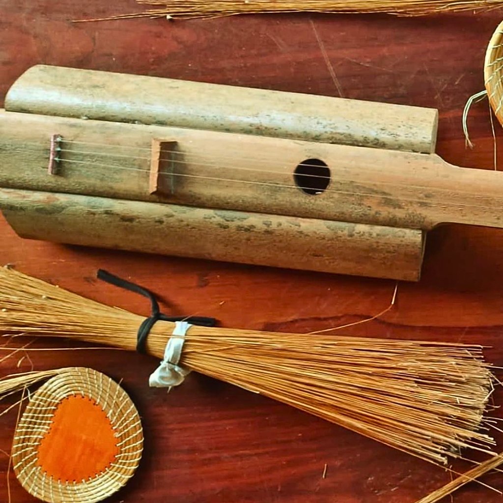 Handcrafted Buriti Wood guitar from Brazil with sustainable design, shown alongside traditional artisan tools on rustic wooden table – Mumbuca Guitars.